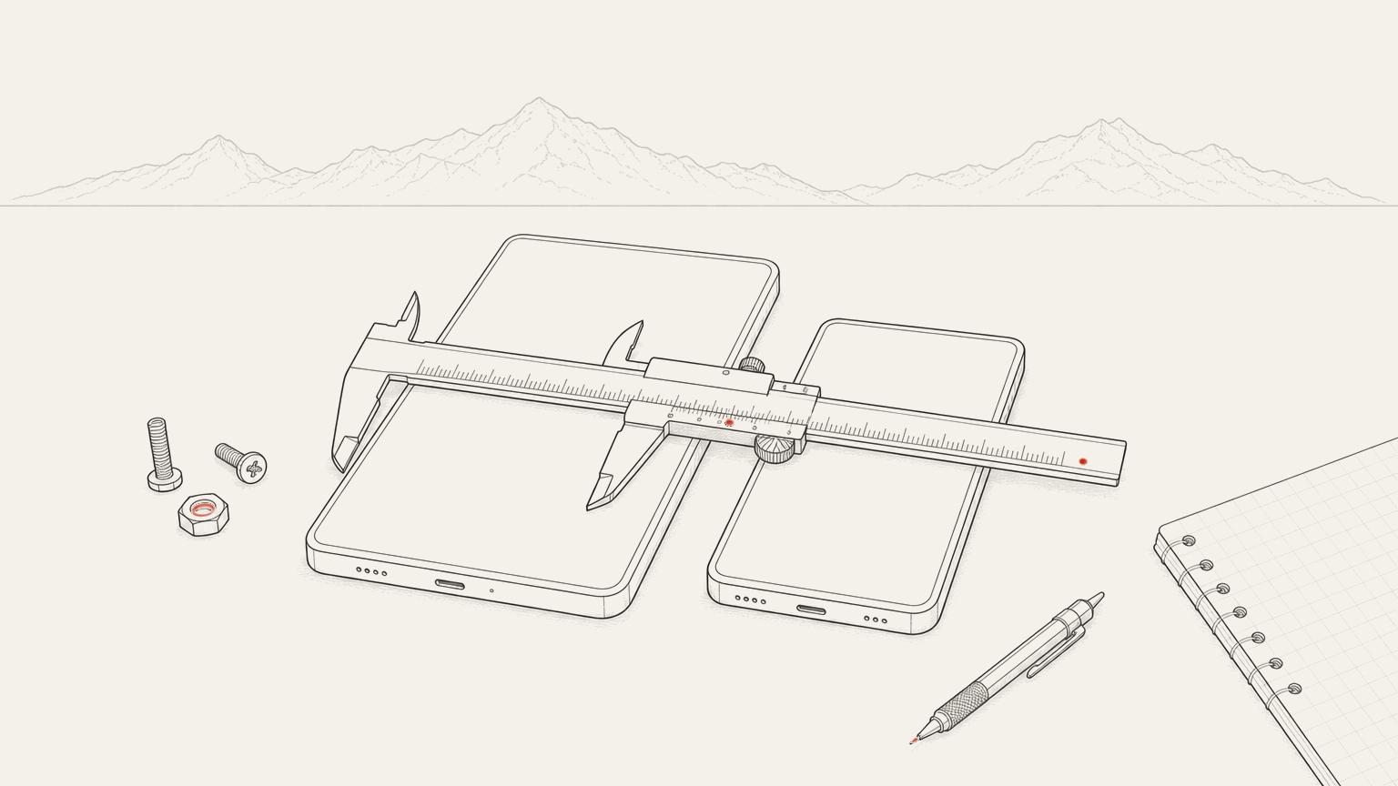 Two handheld devices lying side by side on a bench with a measuring caliper laid across them.